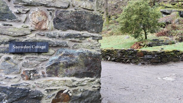 Un muro in pietra con un cartello che riporta la scritta 'Snowdon Cottage'.