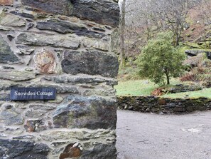 Un muro de piedra con un letrero que dice "Snowdon Cottage".