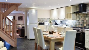 Una cucina moderna con zona pranzo, caratterizzata da una scala in legno, un frigorifero bianco, un piano cottura e uno schienale piastrellato.