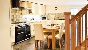 Una cucina con tavolo da pranzo per quattro persone, piano cottura, forno e microonde.