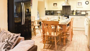Een knus woongedeelte met een eethoek, kitchenette en een bank voorzien van patroonkussens.