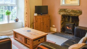 Un salon chaleureux avec une cheminée en pierre, un téléviseur posé sur un meuble en bois et un canapé confortable.