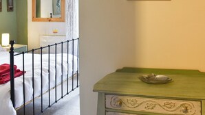 Une chambre à coucher avec un lit, une table de chevet, une commode et un miroir.