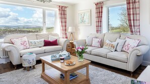 Un salon chaleureux avec deux canapés, une table basse et une vue sur la campagne.