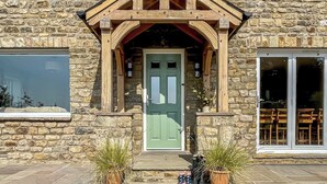 Un bâtiment en pierre avec une porte verte, un porche en bois et des plantes en pot.