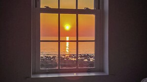 A window with a sunset view of the ocean. - Captains Beach House (Aberdesach)