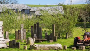 A rustic outdoor setting with a stone wall, wooden fence, and a tractor. - 2 bedroom accommodation in Holbeton (Holbeton)