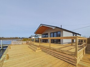 A modern house with a wooden deck, large windows, and a view of the water. - 2 bedroom accommodation in Brundall (Brundall)