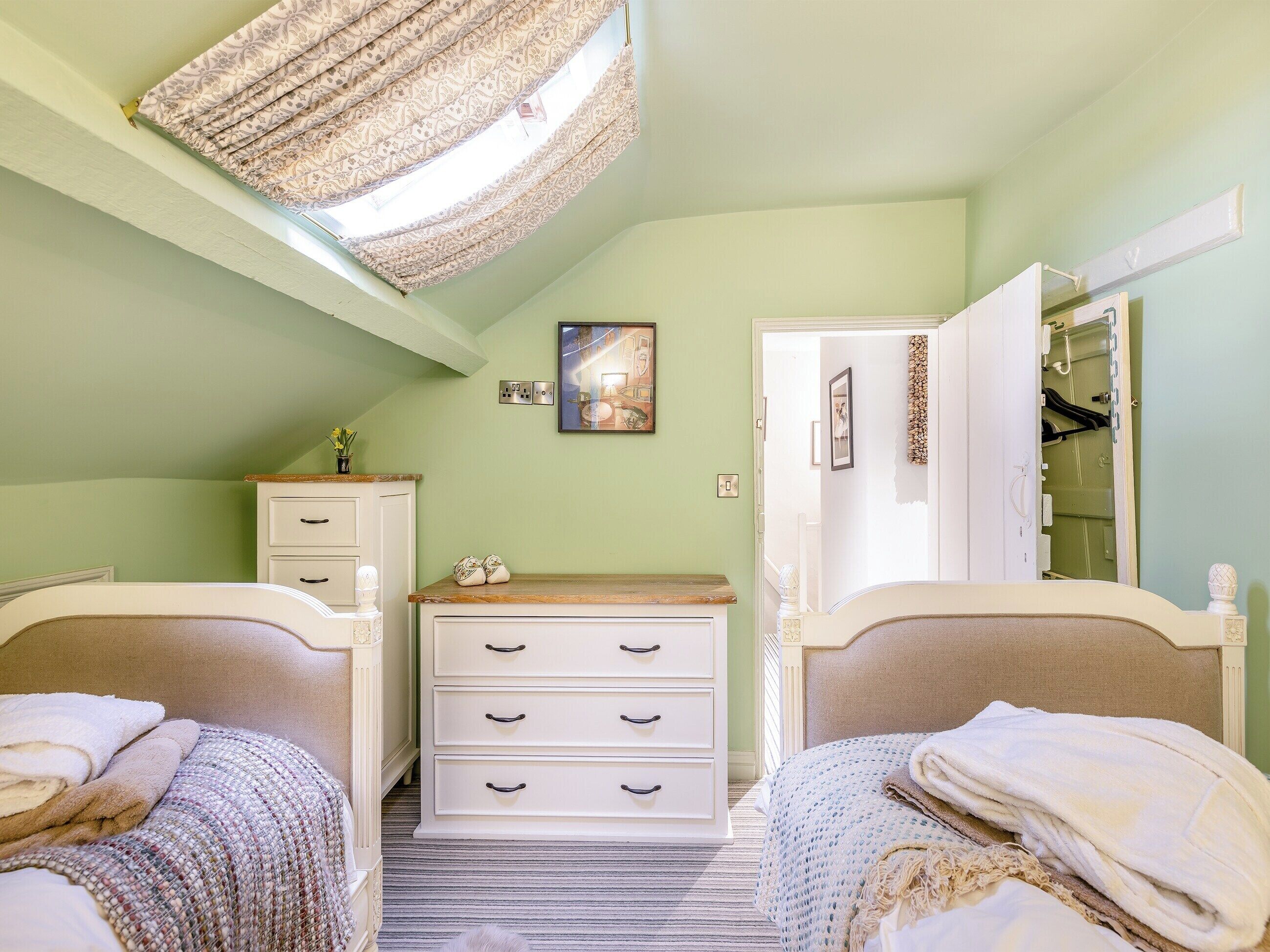 Een slaapkamer met twee bedden, een kaptafel, een spiegel en een plafondlamp.