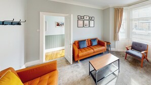 Uma sala de estar com sofá, poltrona, mesa de centro e porta para uma varanda.