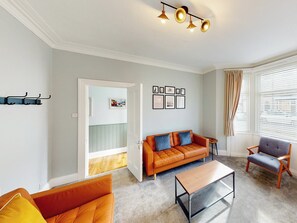 Ein Wohnzimmer mit einer Couch, einem Sessel, einem Couchtisch und einer Tür, die auf einen Balkon führt.