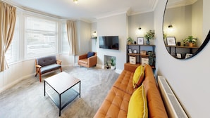 Sala de estar com sofá, poltrona, mesa de centro, televisão e lareira.
