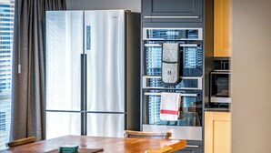 Una cocina moderna con refrigerador, horno y microondas incorporados. Hay una mesa de comedor de madera con sillas.