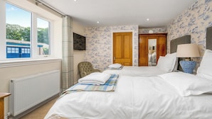 Habitación de hotel con dos camas, vista al exterior, una puerta de madera y un papel tapiz estampado.