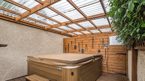 Jacuzzi con escalones de madera y pared de madera con ganchos.
