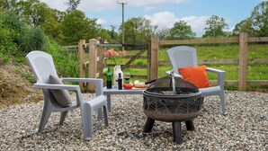 An outdoor seating area with two chairs, a table, and a fire pit. - Little Dunley Cottages - Tiny House (Bovey Tracey, near Newton Abbot)