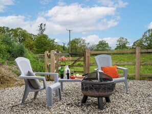 An outdoor seating area with two chairs, a table, and a fire pit. - Little Dunley Cottages - Tiny House (Bovey Tracey, near Newton Abbot)