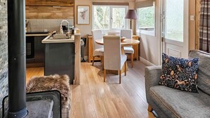 Ein modernes Wohnzimmer mit Kamin, Essbereich und einer Küche mit Steinwand.