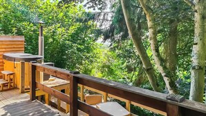 Eine Holzterrasse mit Grill, Sitzgelegenheit und Whirlpool.