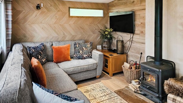 Ein modernes Wohnzimmer mit Ecksofa, Kamin, Flachbildfernseher und einer Wand mit Fischgrätparkett.