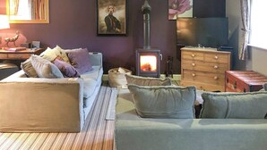 Ett mysigt vardagsrum med en soffa, ett litet bord, en öppen spis, en tv och en byrå.