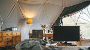 A tented accommodation with a wooden desk, a lamp, a trophy, and a computer monitor. - The Star Dome - UKC6978 (Ludlow)