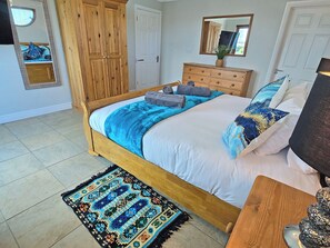 Quarto com cama de madeira, penteadeira, espelho e tapete estampado.