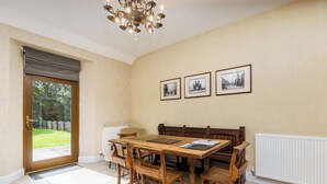 Ein Esszimmer mit Holztisch und Stühlen, einer Kronleuchter und drei gerahmten Bildern an der Wand.