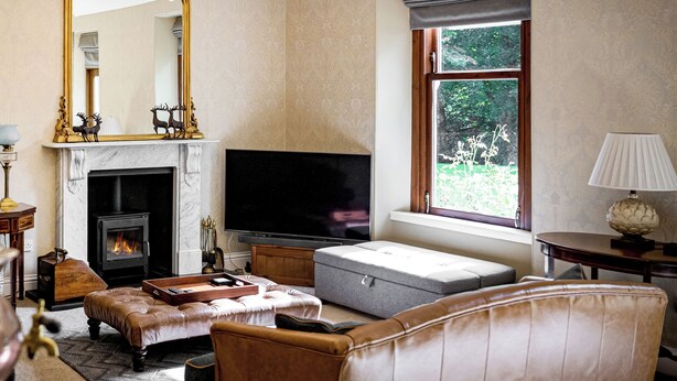 Ein Wohnzimmer mit Kamin, Fernseher und Sitzgruppe.