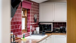 Eine Küche mit weißen Schränken, einer Mikrowelle, einem Toaster und einem Spülbecken mit Geschirrgestell.