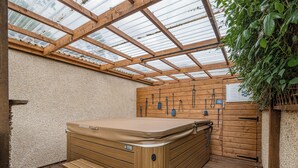Ein Whirlpool mit Holzstufen, einer Holzwand und einer Glaskuppel.