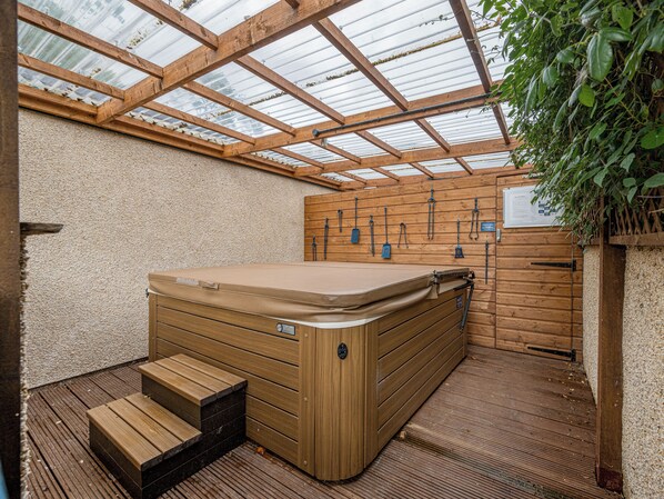 A hot tub with wooden steps, a wooden wall, and a glass ceiling.