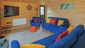 A cozy room with a blue sofa, a red chair, and a wooden ceiling. - Ferry Lodge - UKC7073 (Brundall)