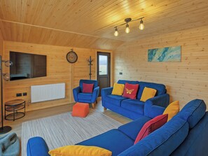 A cozy room with a blue sofa, a red chair, and a wooden ceiling. - Ferry Lodge - UKC7073 (Brundall)