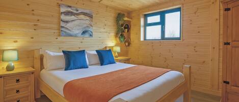 A wooden-paneled bedroom with a bed, bedside tables, a window, and a painting on the wall.