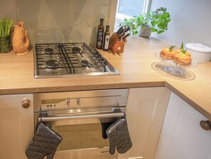 Une cuisine équipée d’une cuisinière, d’un four et d’un plan de travail en acier inoxydable, ainsi que d’un comptoir en bois.