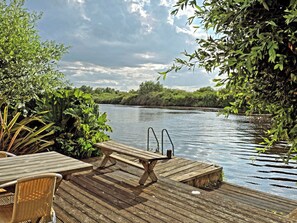 A wooden deck with a pool table and chairs, overlooking a calm river with dense greenery on the banks. - Dinky Daze - UKC7071 (Brundall)