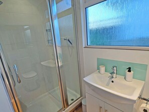 A bathroom with a glass shower enclosure, a sink with a mirror, and a window with a view. - Dinky Daze - UKC7071 (Brundall)