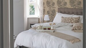 A neatly made bed with a white duvet, a bedside table with a lamp, and a tray with a teapot and cups. - 2 bedroom accommodation in Birnam (Birnam)