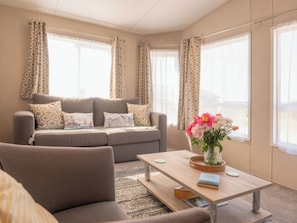Ein modernes Wohnzimmer mit einer Couch, einem Couchtisch und einem Blumenarrangement.
