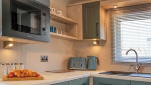 A kitchen with a microwave, toaster, kettle, and a breakfast tray with croissants and strawberries. - 18 Ocean Terrace - UKC7117 (Ilfracombe)