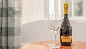 En flaske Riflessi Prosecco på et træbord med to tomme vinglas ved siden af.