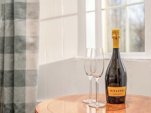 Une bouteille de Prosecco Riflessi sur une table en bois, avec deux verres à vin vides à côté.