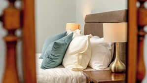 En pænt redt seng med puder og et natbord med en lampe.
