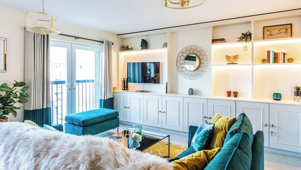 A living room with a sofa, a television, a large dog, and a decorative mirror.