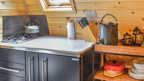 Et kompakt køkken med gaskogeplade, kaffemaskine og elkedel på bordpladen.