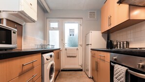 Eine kleine Küche mit Waschmaschine, Mikrowelle, Kühlschrank und Backofen.