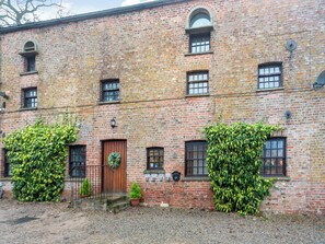 Un bâtiment en briques avec une porte en bois, des fenêtres et une allée gravillonnée.