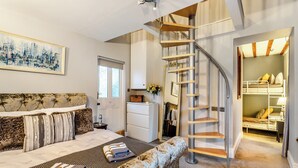Una camera da letto con un letto, un divano, una scala, un armadio e un quadro appeso al muro.