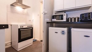 Cozinha compacta com fogão, forno, micro-ondas e uma geladeira pequena.